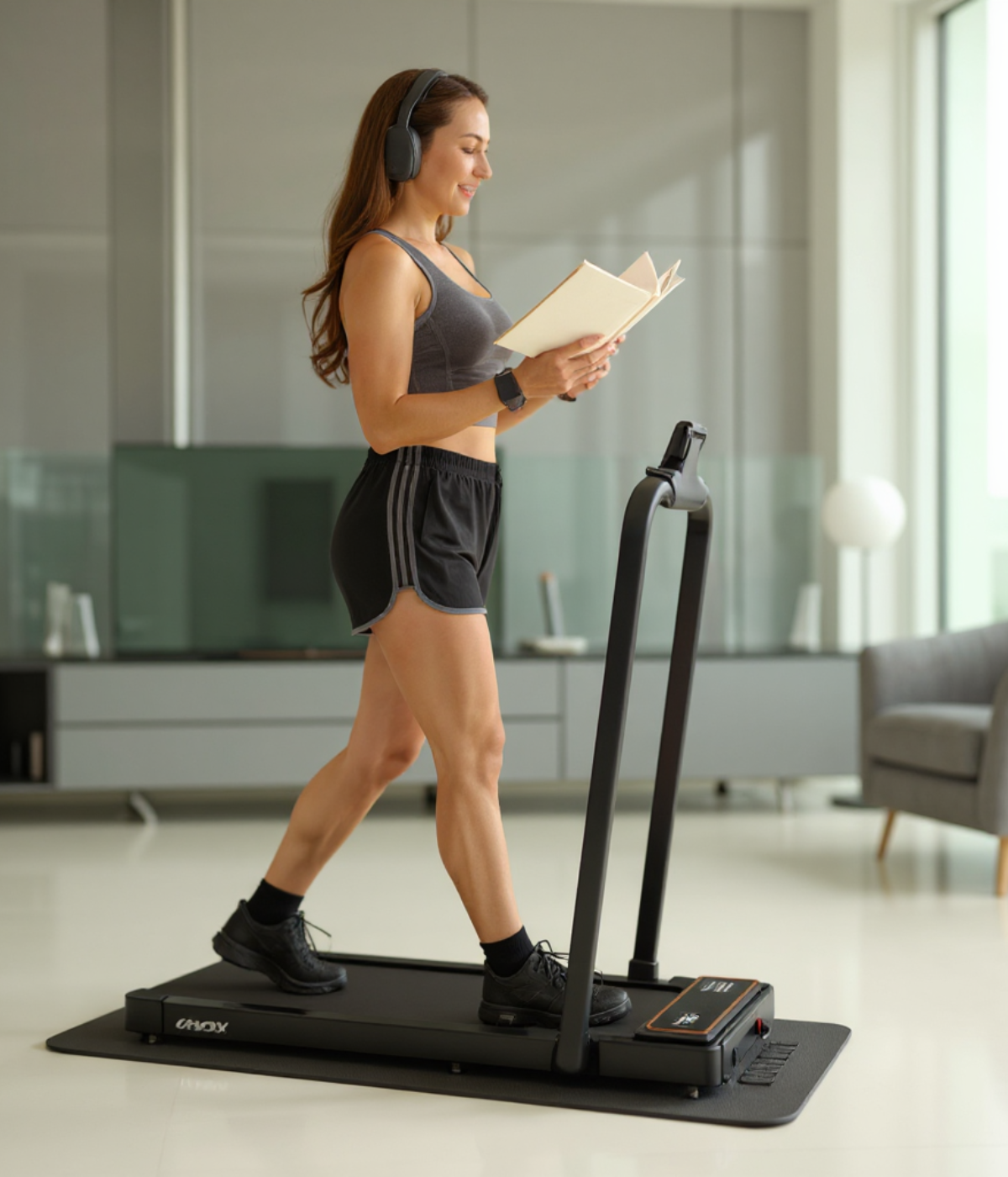 Femme lisant un livre tout en marchant sur un tapis inclinable.